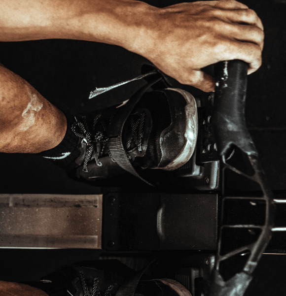 Person rowing on exercise machine, close-up view.