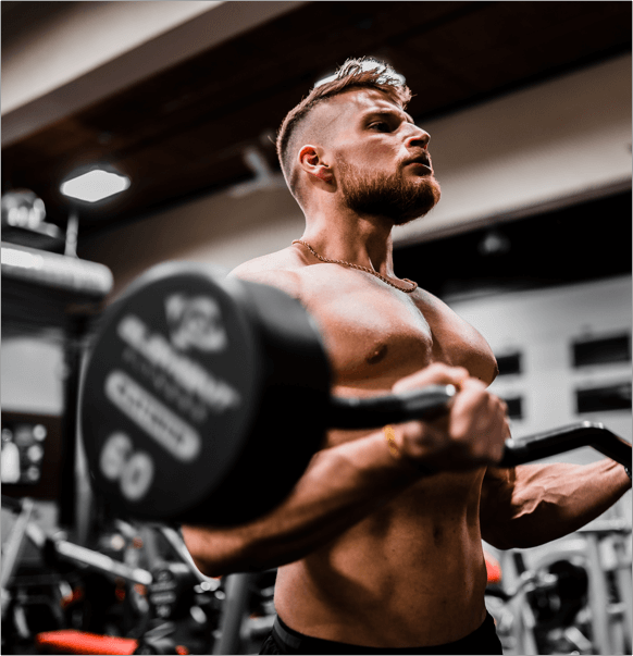Muscular man performing barbell curl in gym