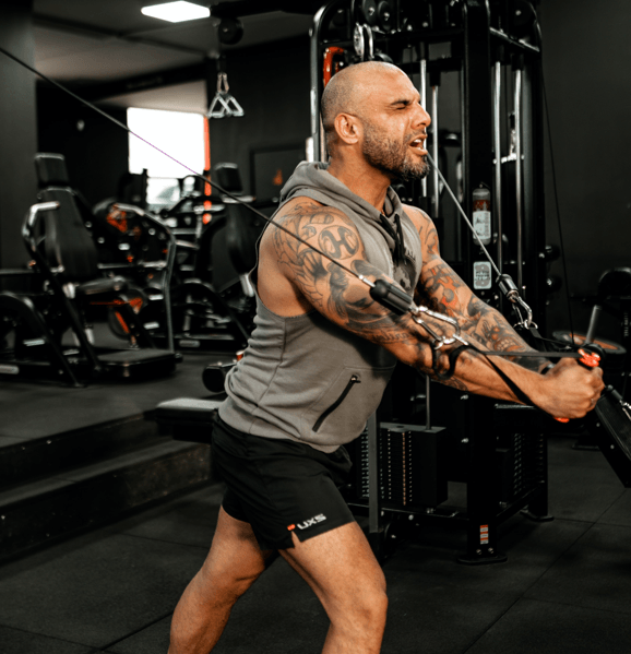 Man exercising with cable machine in gym.